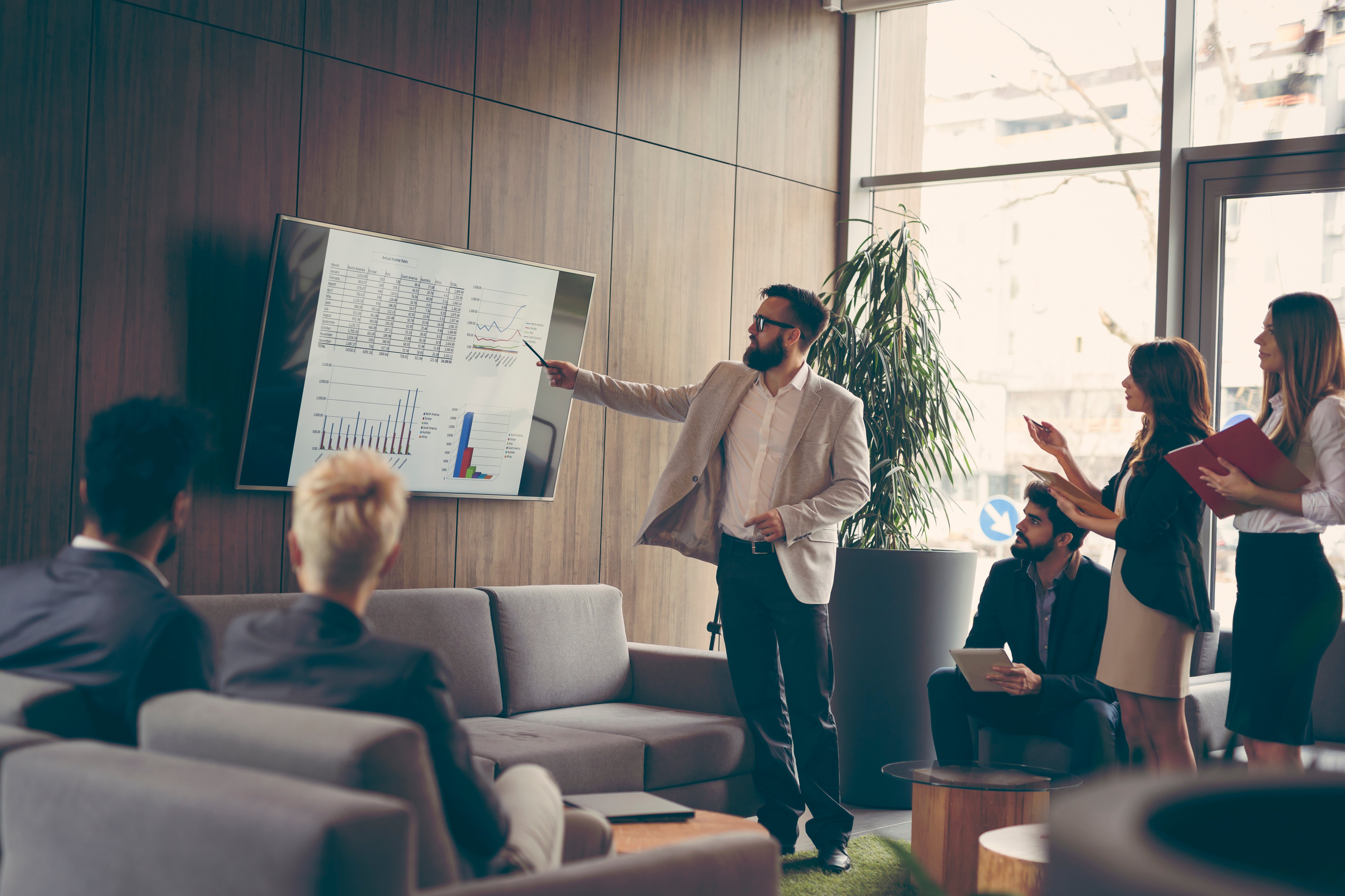 Professional business man presenting on TV screen with team surrounding and watching