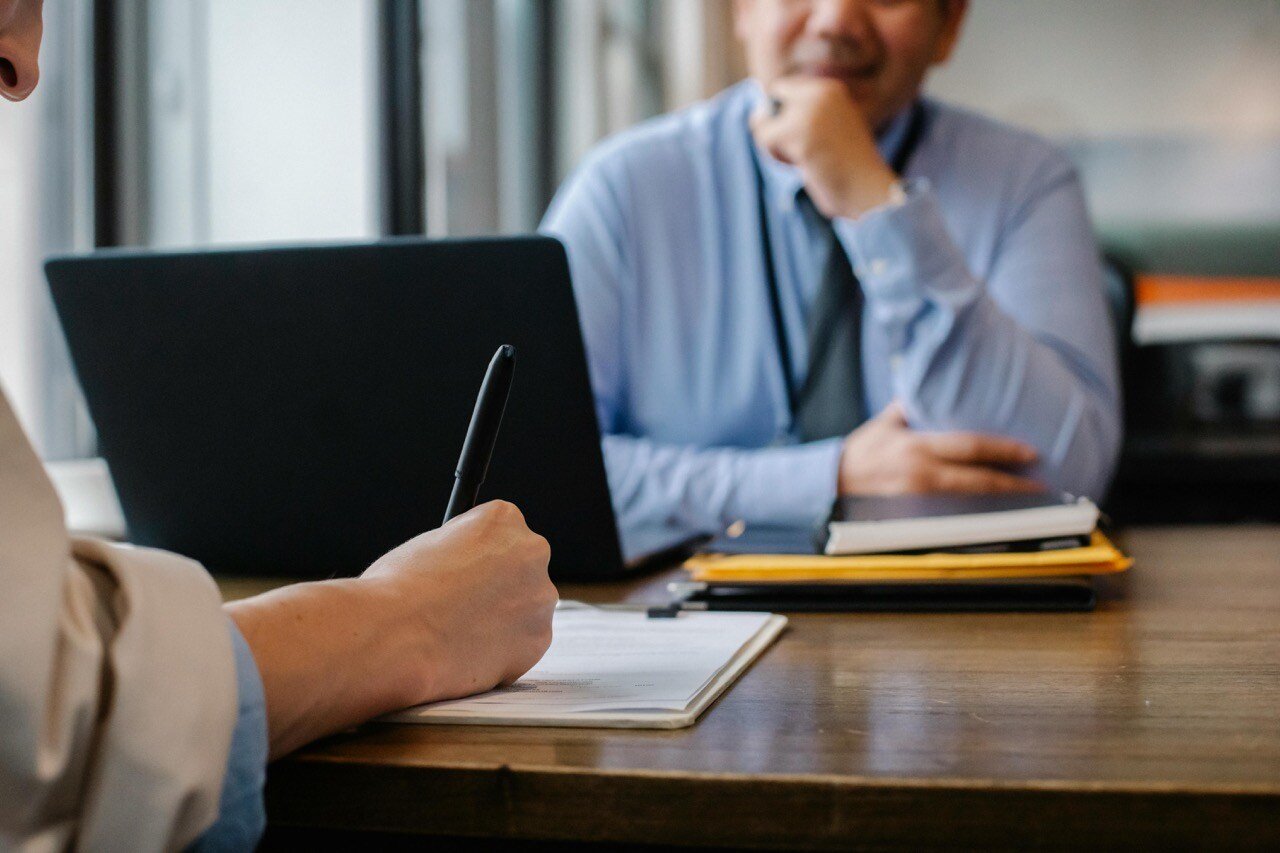 Sales candidate sitting across office table from hiring manager for a job interview.