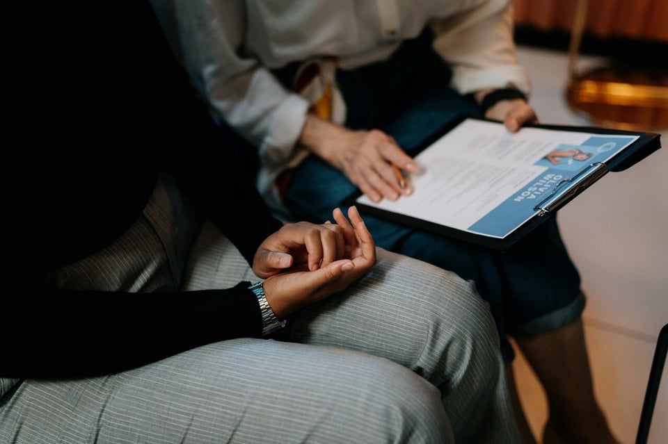 Two professionals sitting beside each other looking at resume on clipboard